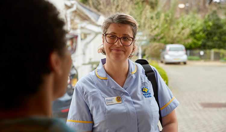 Marie Curie Nurse speaking with someone at their front door.