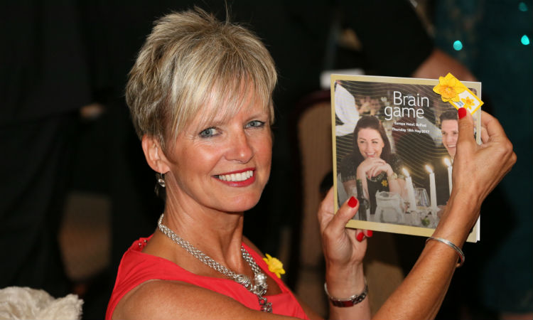 A Belfast Brain Game 2017 guest smiles as she holds up the programme