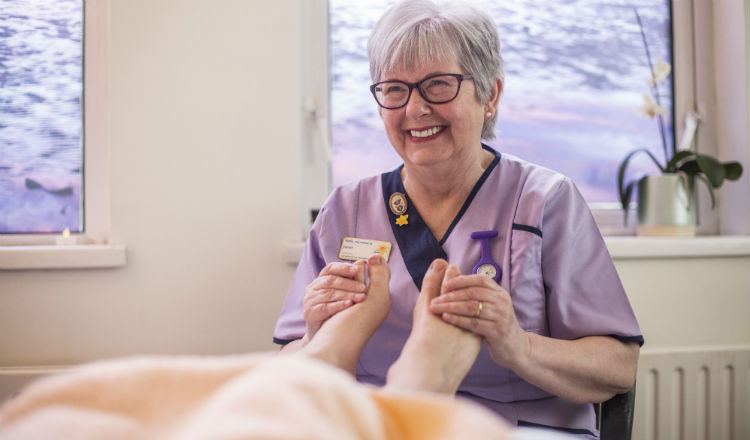 A hospice worker gives a foot massage to a patient