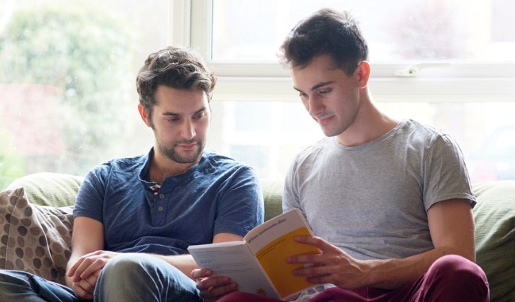 two men reading Marie Curie booklet